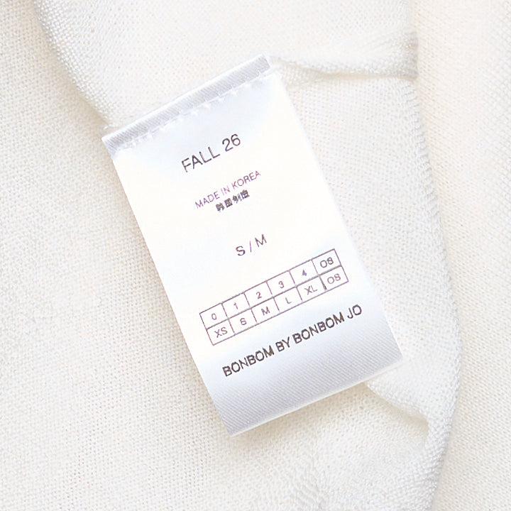 Back view of Bonbom Shoulder Tuck Sleeveless Top in off-white, showing tuck detailing at the shoulders, relaxed boxy silhouette, and woven Bonbom label at the hem