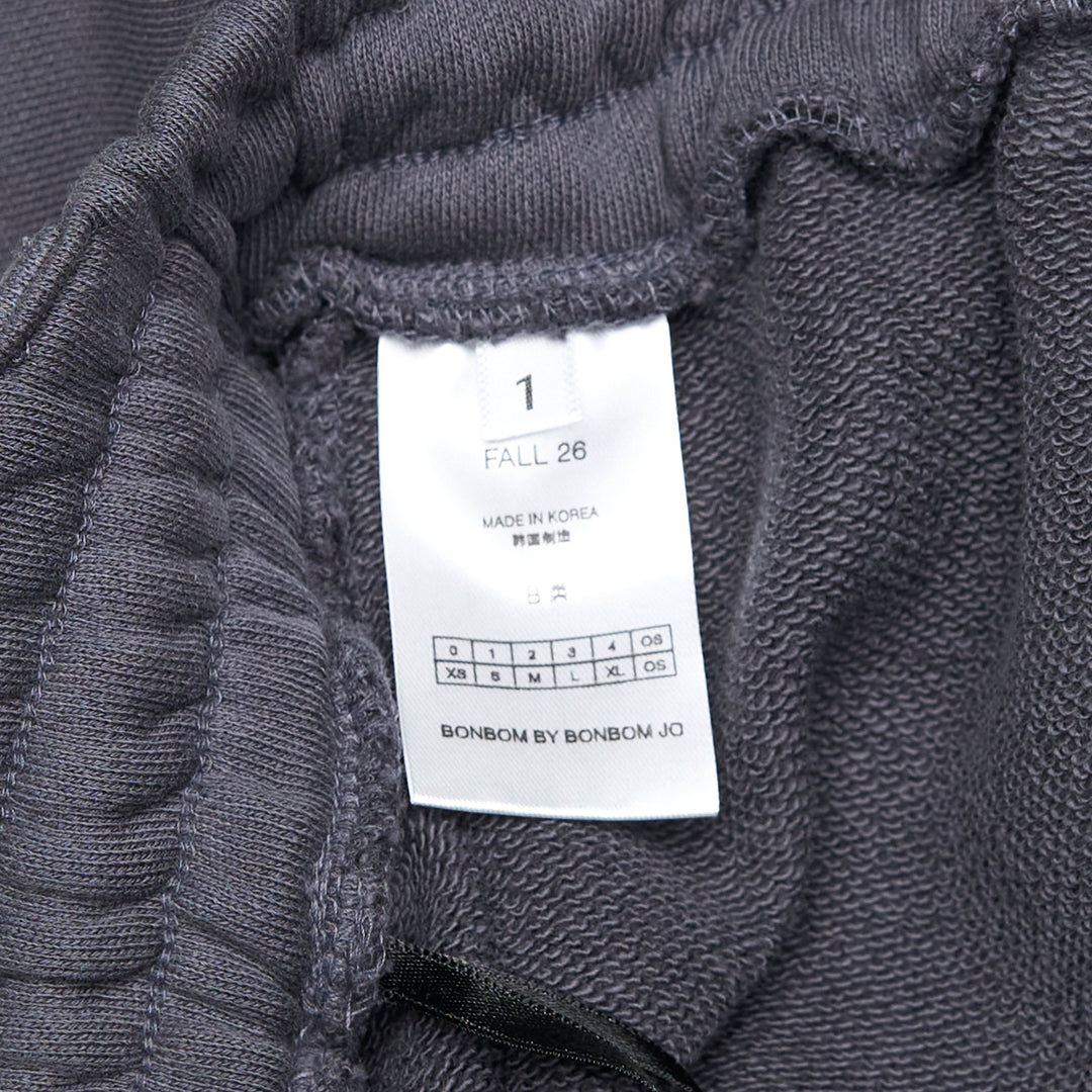 Bonbom Giant Front-Volume Mini Skirt in washed dark navy heavyweight fleece, featuring an elasticated drawstring waistband, belt loop detailing, side patch pocket, and a small woven Bonbom logo label at the lower front