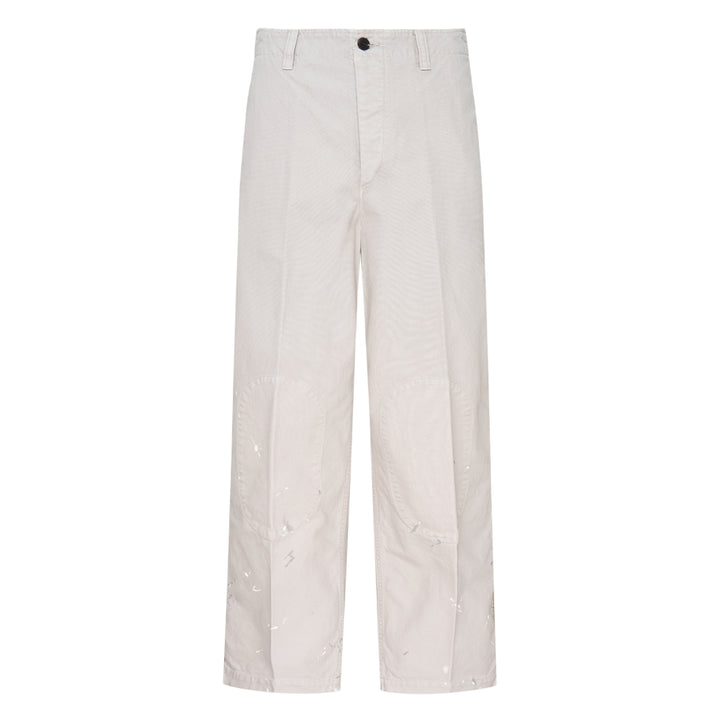visvim Survey Damaged Pants in light stone, wide-leg silhouette with paint-splatter distressing on lower leg panels, front view on white background