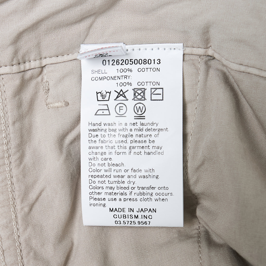visvim Survey Damaged Pants in light stone, wide-leg silhouette with paint-splatter distressing on lower leg panels, front view on white background - view 3