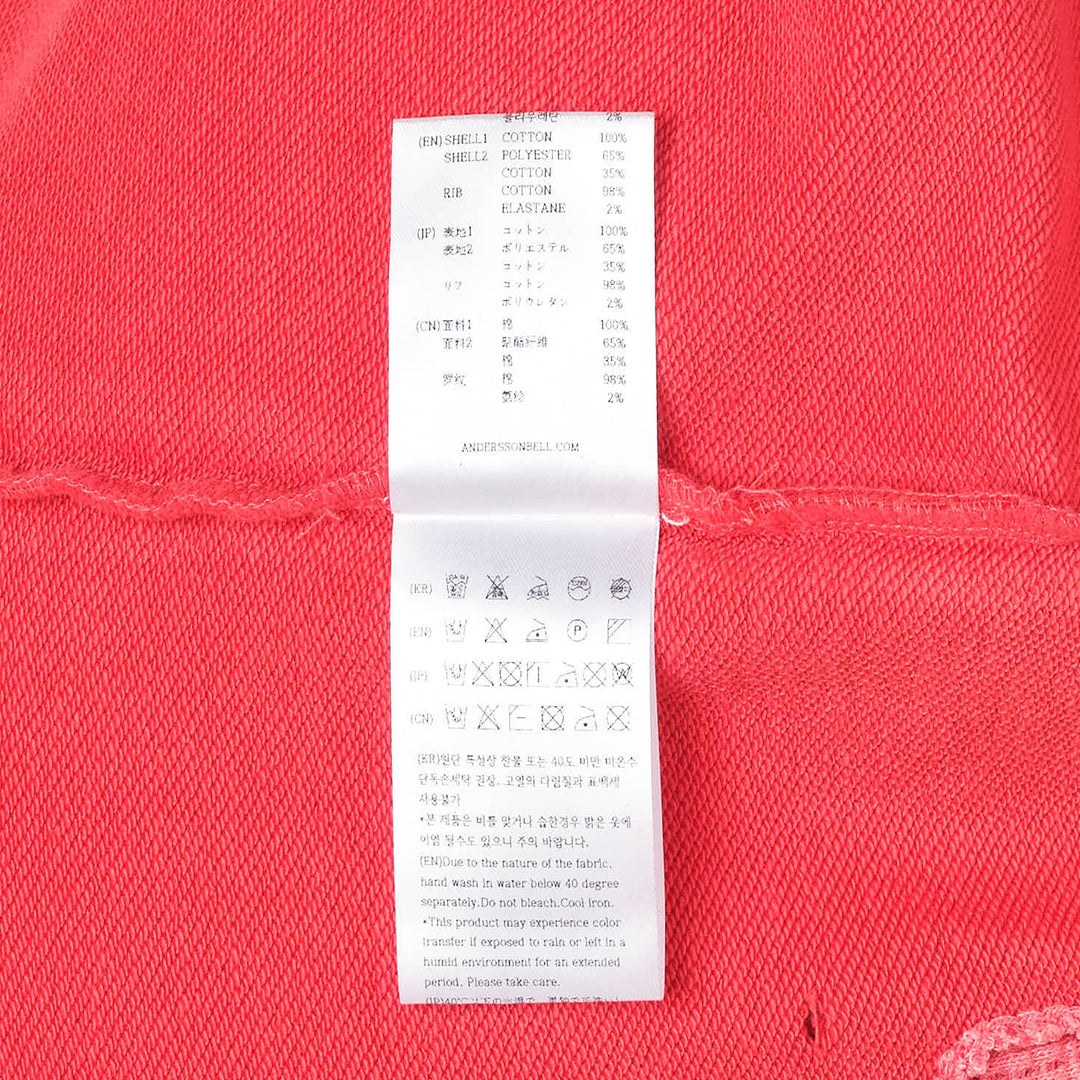 Andersson Bell unisex spray washed distressed hoodie in red with gold 'Again?' script graphic, lip-print motif, intentional slub holes, and raw-edge hem detailing — flat lay front view