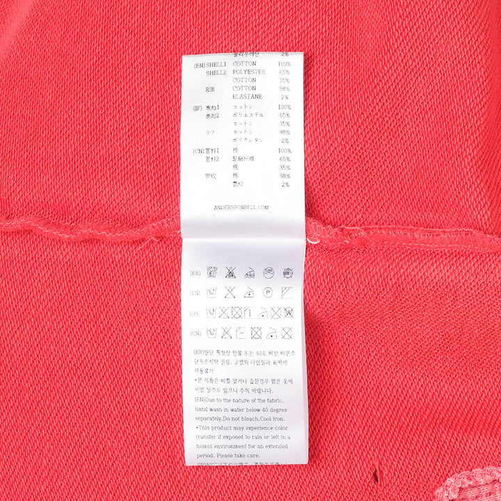 Andersson Bell unisex spray washed distressed hoodie in red with gold 'Again?' script graphic, lip-print motif, intentional slub holes, and raw-edge hem detailing — flat lay front view