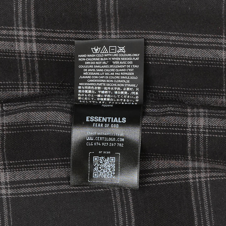 Fear of God Essentials long sleeve plaid button-up shirt in dark navy and grey windowpane check, relaxed oversized fit with concealed placket and tonal buttons, flat lay on white background