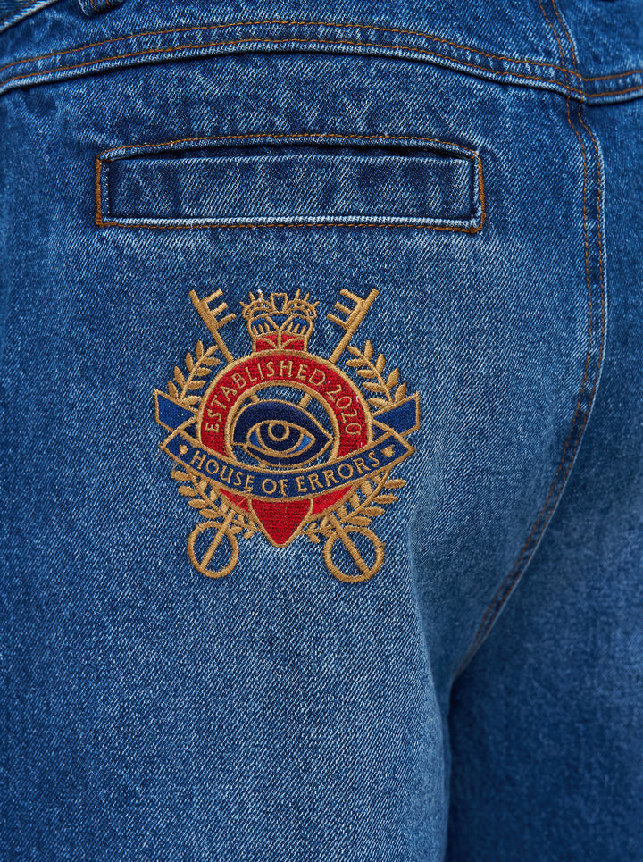 House of Errors Crown Jeans in mid-wash blue denim with whiskered fading, wide-leg cut and gold-tone engraved button, shown flat from the front - view 4