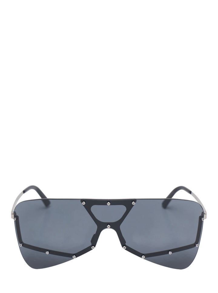 Rick Owens oversized shield mask sunglasses with dark smoke single lens, geometric black frame with triangular bridge cutout, silver stud hardware, and slim metal temples, front view