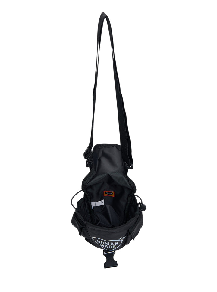 Human Made Military Pouch #1 in black nylon, featuring woven webbing harness, dual D-ring attachments, buckle-release closure, and a detachable adjustable shoulder strap, shown on a white background - view 3