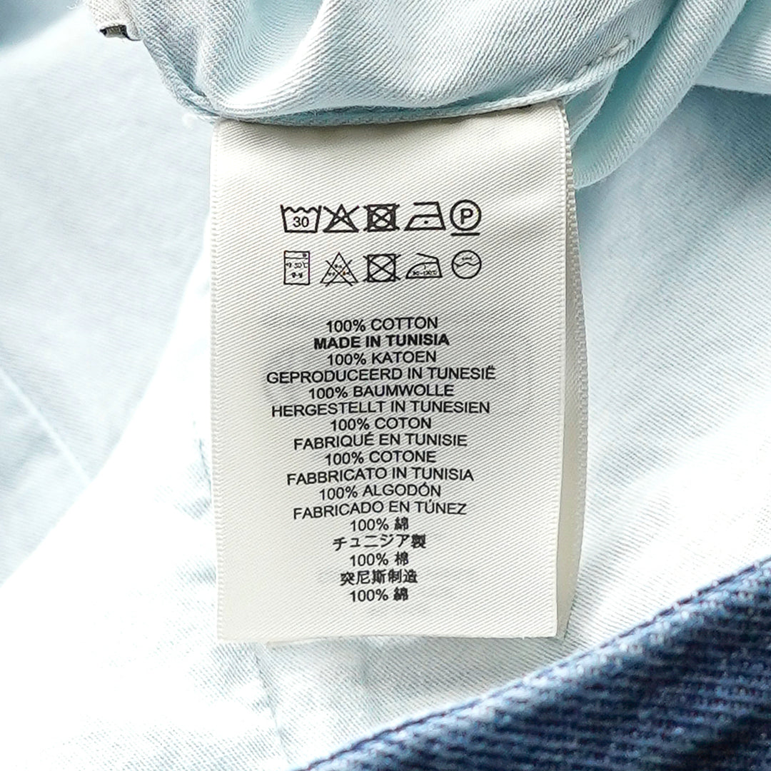 Dries Van Noten indigo wash denim midi skirt with buttoned flap pockets, inverted pleats, and a structured A-line silhouette, photographed flat on a white background - view 3