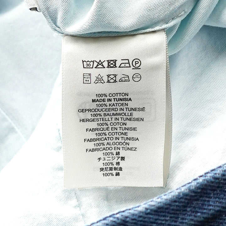 Dries Van Noten indigo wash denim midi skirt with buttoned flap pockets, inverted pleats, and a structured A-line silhouette, photographed flat on a white background - view 3