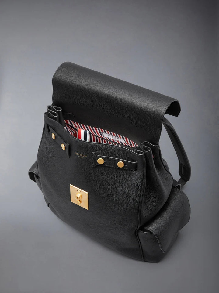 Thom Browne Bolton backpack in black soft pebble leather with brass-tone lock closure, flap side pockets, and red, white, and blue tab detail - view 3