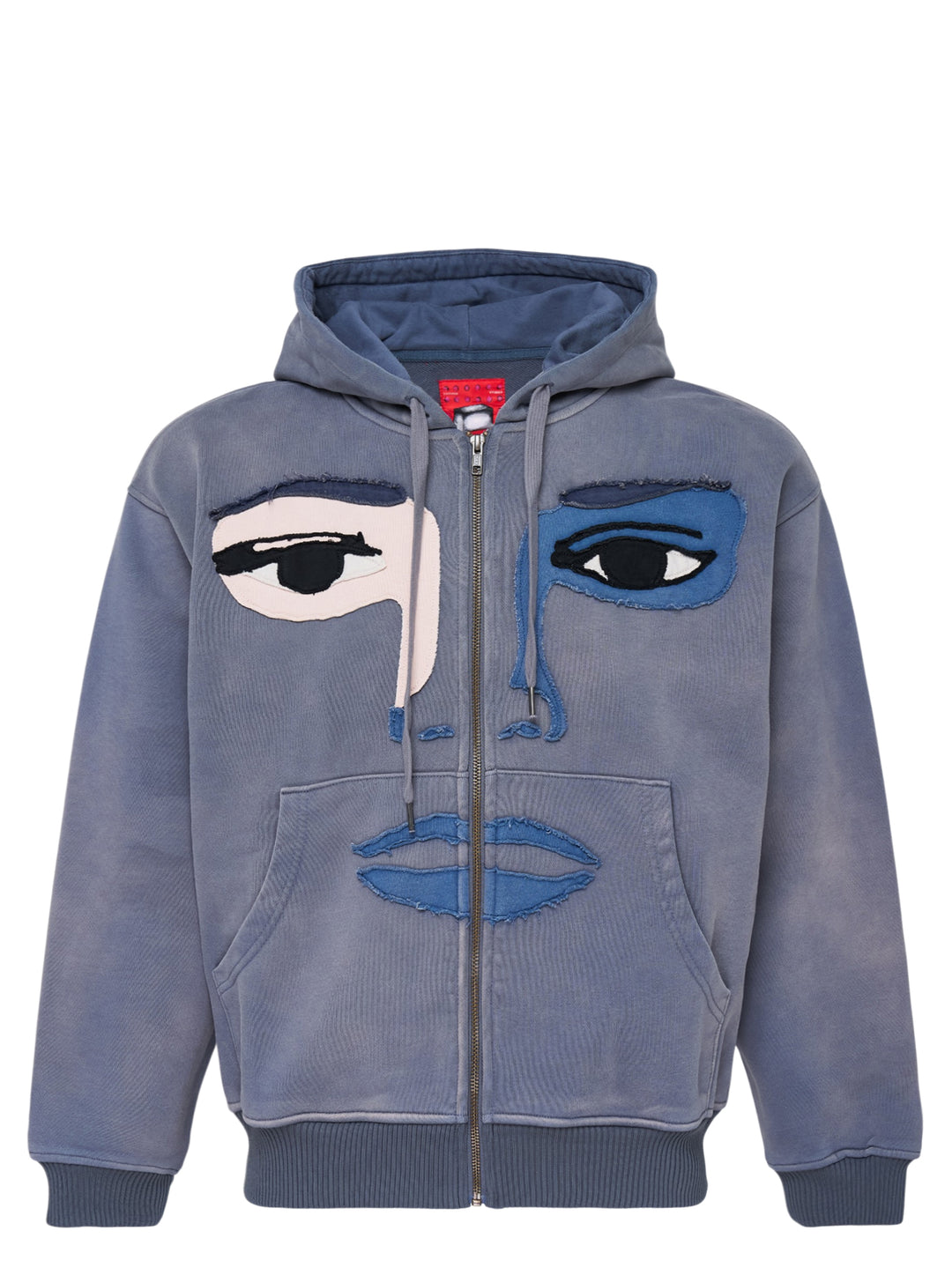KidSuper Studios washed blue-grey zip hoodie with a patchwork appliqué face featuring mismatched eyes, nose and lips, shown from the front with drawstring hood and kangaroo pocket