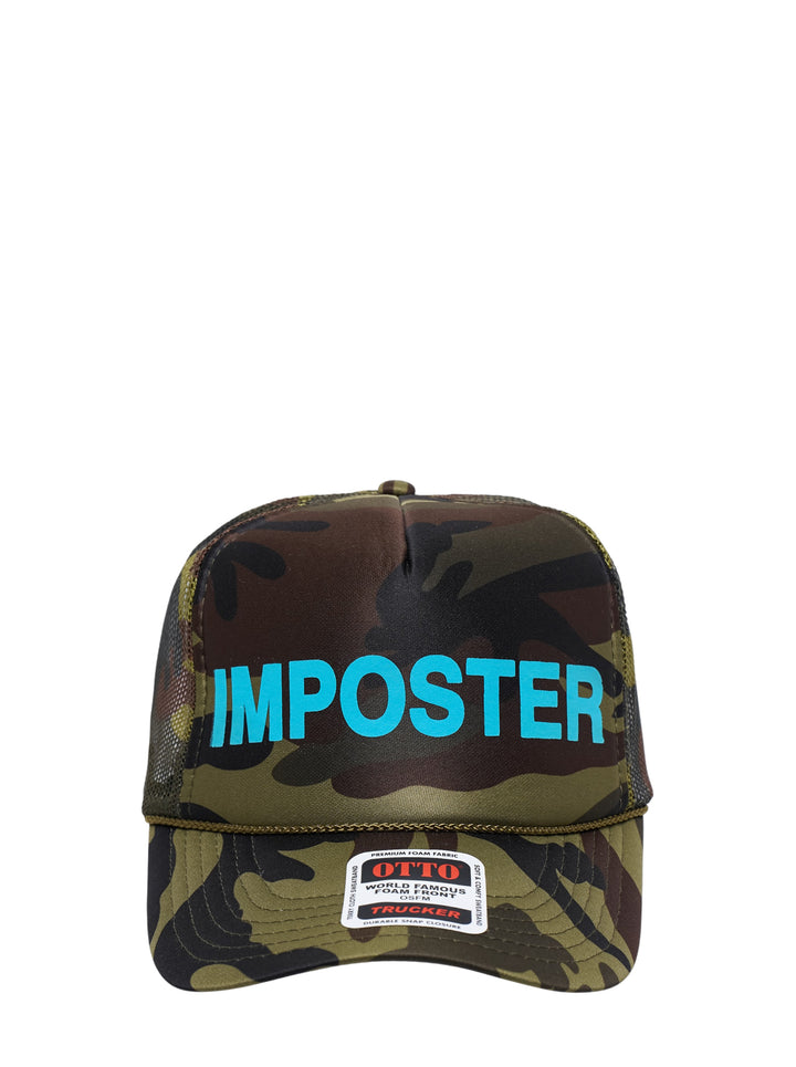 Ashley Williams Camo Imposter Trucker Hat in woodland camouflage with bold cyan embroidered 'IMPOSTER' lettering across the structured foam front panel