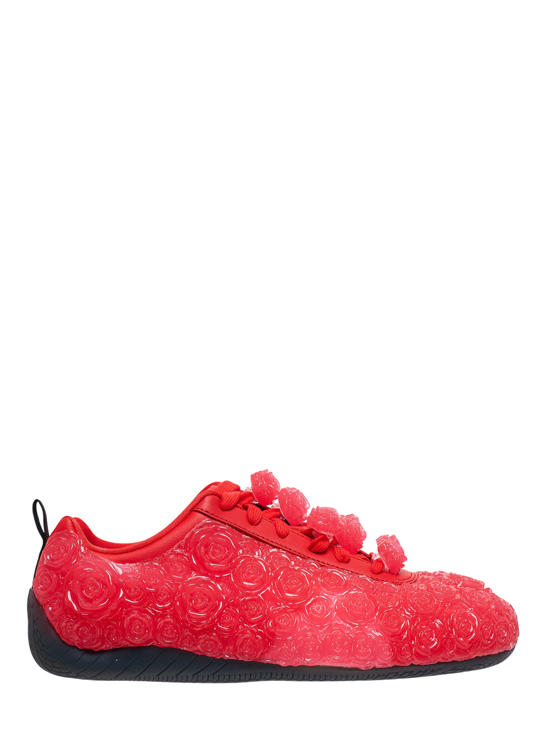 Noir Kei Ninomiya red low-top sneaker with translucent embossed rose details, rose-shaped lace toggles and a black rubber sole, shown in side profile
