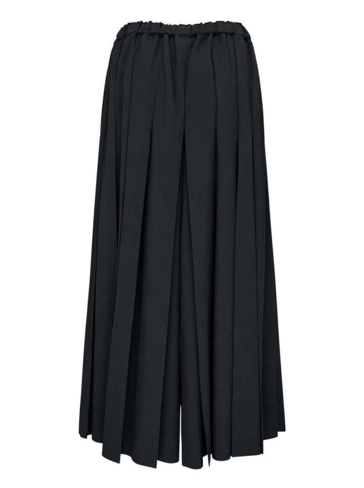 Comme des Garçons black pleated wide-leg trousers with elasticated waistband and fluid, midi-length silhouette, displayed flat on a white background - view 2
