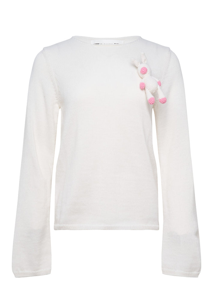 Comme des Garçons Girl ivory long sleeve fine knit top with 3D crochet unicorn appliqué in white and pink on the chest, crew neckline, flat lay on white background