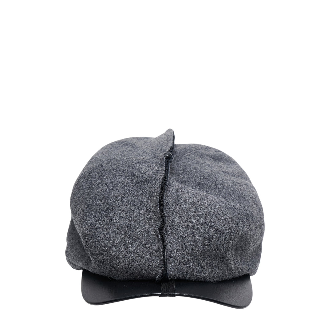 Comme des Garçons Shirt black Gavroche cap with exposed raw centre seam and faux-leather brim, front view on white background
