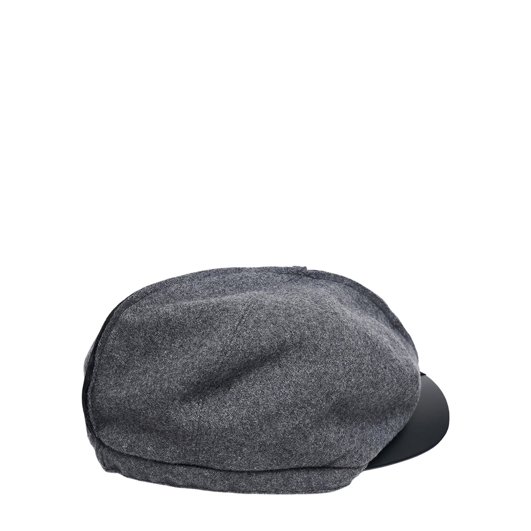 Comme des Garçons Shirt black Gavroche cap with exposed raw centre seam and faux-leather brim, front view on white background