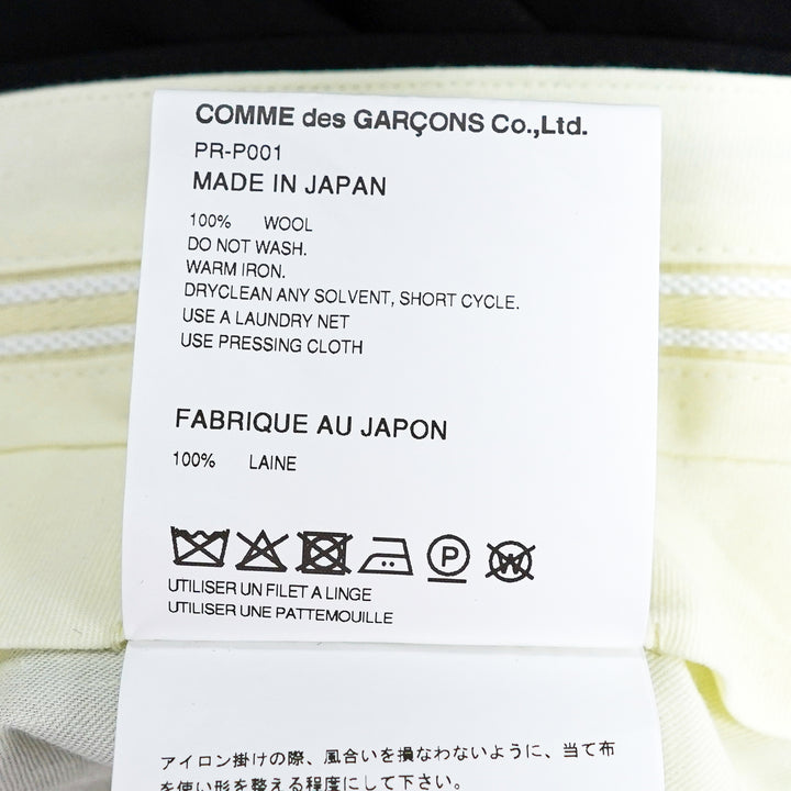 Comme des Garçons Homme Plus black wool tropical wide-leg pants with sculptural knotted bow and cascading ribbon hem trim, front view on white background - view 3