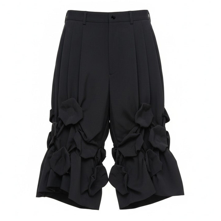 Comme des Garçons Homme Plus black wool tropical shorts with knotted fabric floral clusters and voluminous ruffled hem, front view on white background