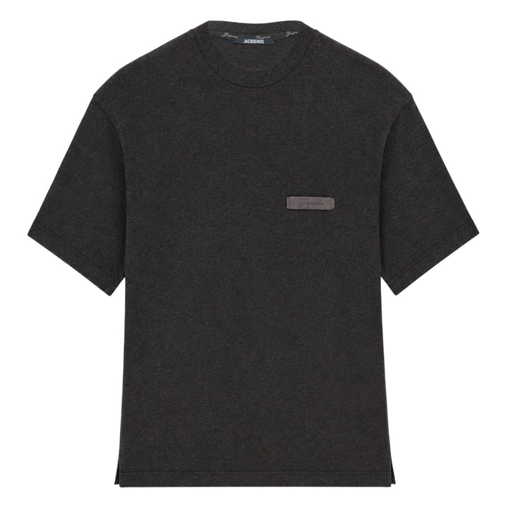 Jacquemus Le T-Shirt Ruban in charcoal grey, featuring a boxy silhouette, crew neckline, and a tonal signature woven label patch at the chest