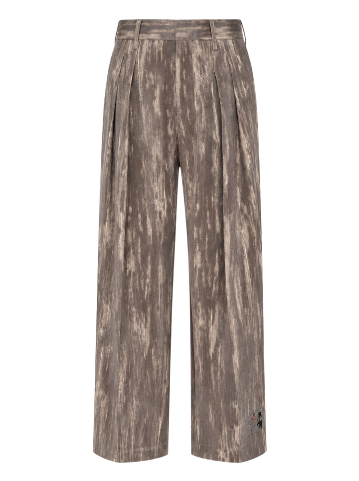 doublet Dust Flocky Trousers in a mottled earthy brown abstract print, featuring wide-leg cut with front pleats and embroidered graphic at the hem, displayed flat on white background