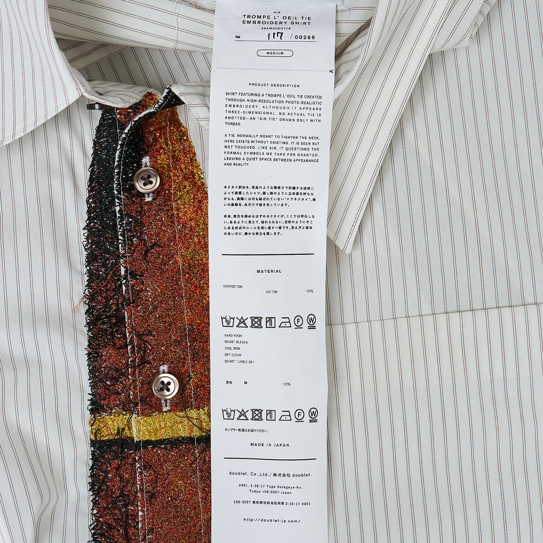 doublet Trompe L'Oeil Tie Embroidery Long Sleeve Shirt in light blue pinstripe with a navy sequined and fringed embroidered tie and embellished tie bar detail on the front placket, shown flat on white background