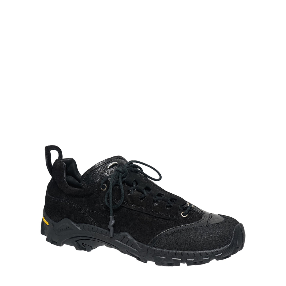 Our Legacy Gabe Stealth low-top sneaker in all-black suede with leather overlays, metal eyelets, toggle lace detail, and Vibram lug outsole, shown in profile