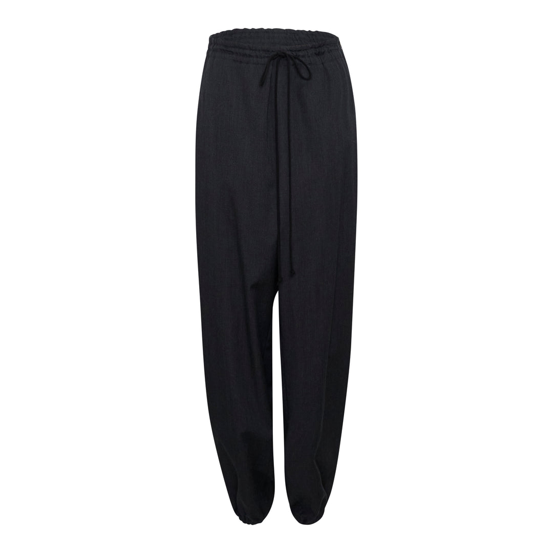 Y's black relaxed-fit drawstring joggers with drop-crotch silhouette, elasticated high-rise waistband with tonal tie, and gathered ankle cuffs, displayed flat on a white background