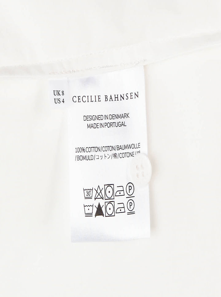 Cecilie Bahnsen Frina cropped white cotton shirt with bow-tied flared cuffs, tonal floral embroidered chest pocket, and button-through front placket, displayed flat on a white background - view 3
