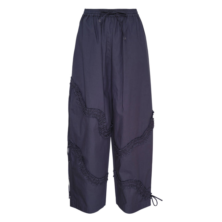 Hisu Park Ruffle Drawstring Trousers in navy, featuring wide barrel-leg silhouette with curved gathered ruffle seams and satin ribbon ties across both legs, elasticated drawstring waistband