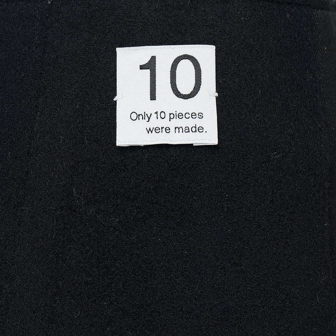 RE;CODE Slit H-Line Skirt in black, featuring a slim pencil silhouette, front slit with layered underlap, raw-fringed waistband, and woven brand label