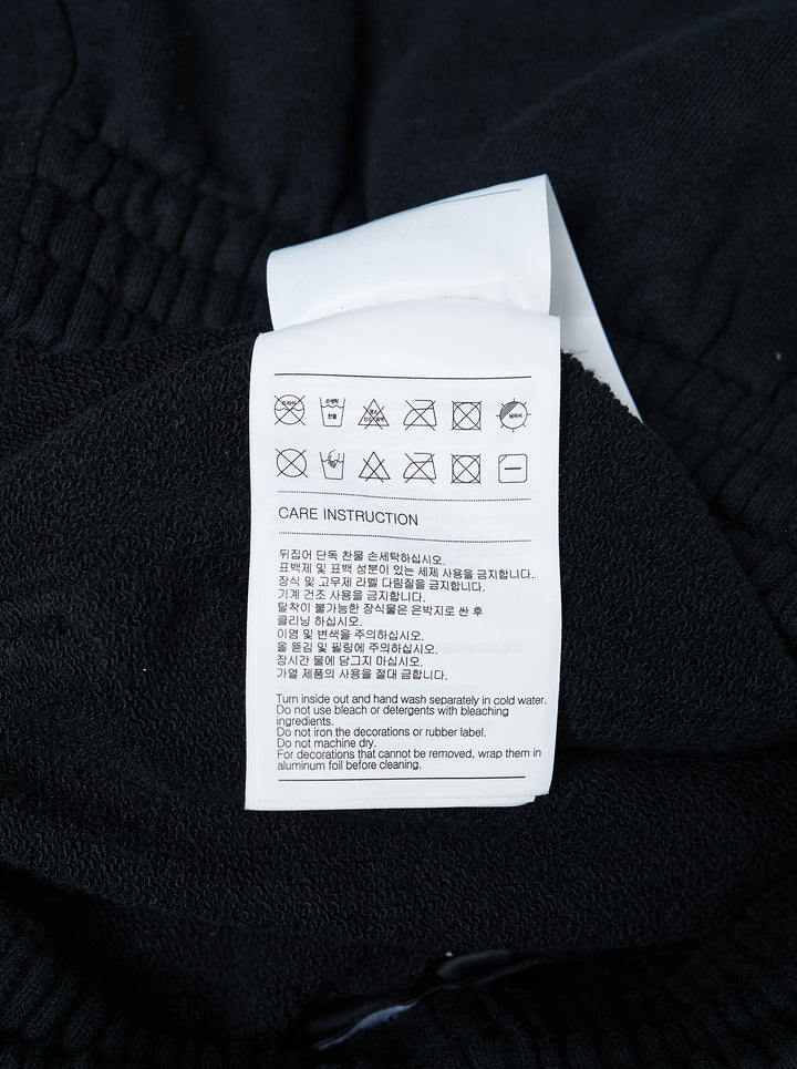 We11done Black Repaired Sweatpants with amber tartan plaid knee patch and embroidered logo, wide-leg relaxed fit, elasticated waistband, front view on white background - view 3