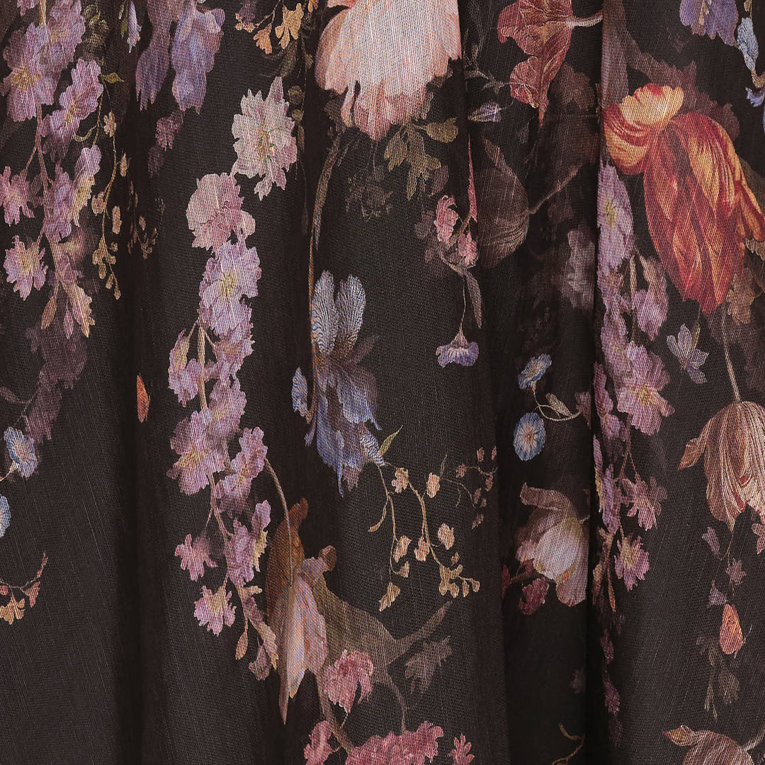 Zimmermann Valiant Corset Picnic Dress in dark botanical floral print, featuring a ruched sweetheart bodice with pom-pom trim, thin spaghetti straps, a branded satin ribbon bow at the waist, and a full semi-sheer A-line midi skirt