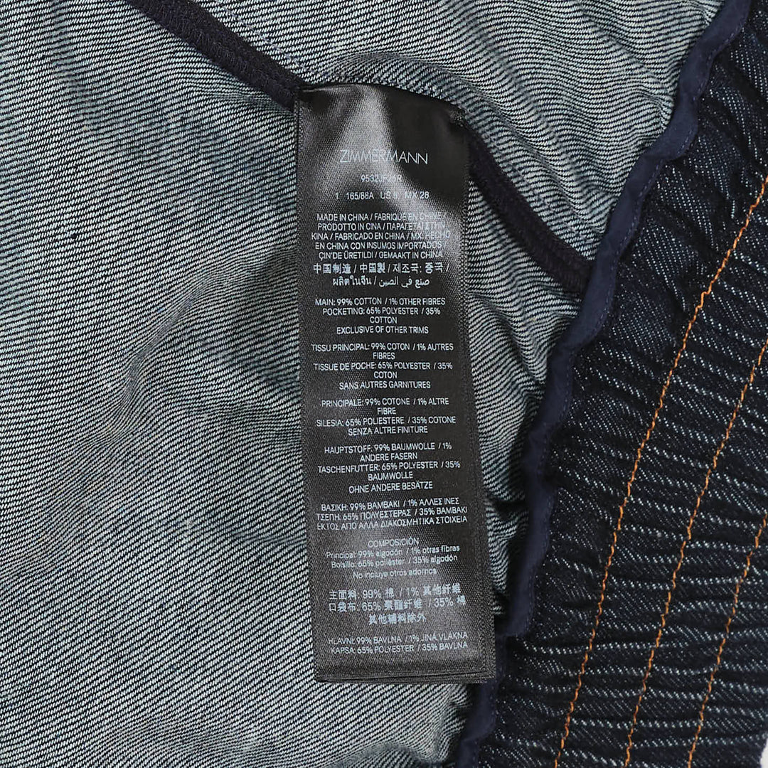 Zimmermann Denim Cape Top in dark indigo, back view, showing V-shaped gathered yoke, amber contrast topstitching, structured collar, and full sweeping hemline