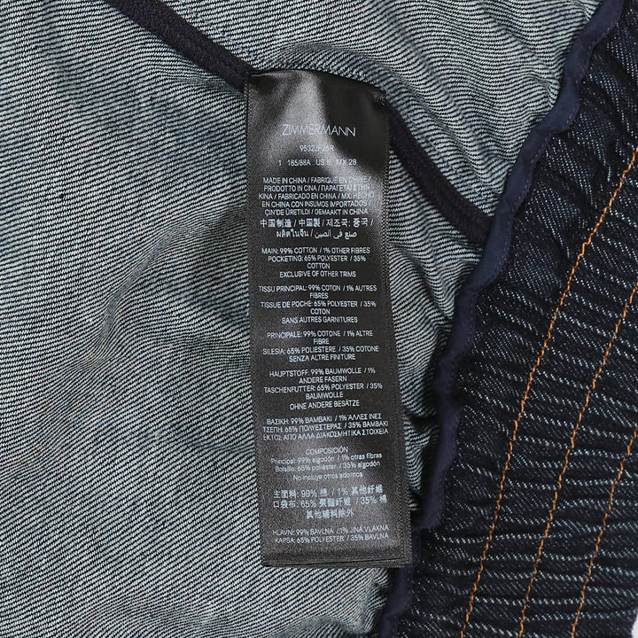 Zimmermann Denim Harem Pants in raw indigo with V-yoke high waist, voluminous balloon legs, gathered ankle cuffs, and contrast gold topstitching — front view on white background
