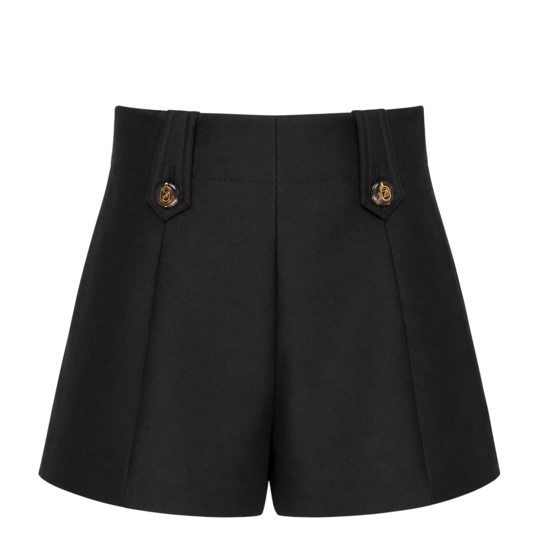 Zimmermann Valiant Tailored Shorts in black with high-rise waistband, A-line silhouette, and signature gold logo button tabs at the waist, shown on a white background