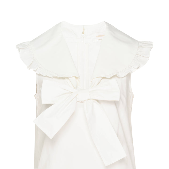 SHUSHU/TONG white sleeveless woven top with ruffled shawl collar and large oversized self-fabric bow at the centre front, photographed against a white background