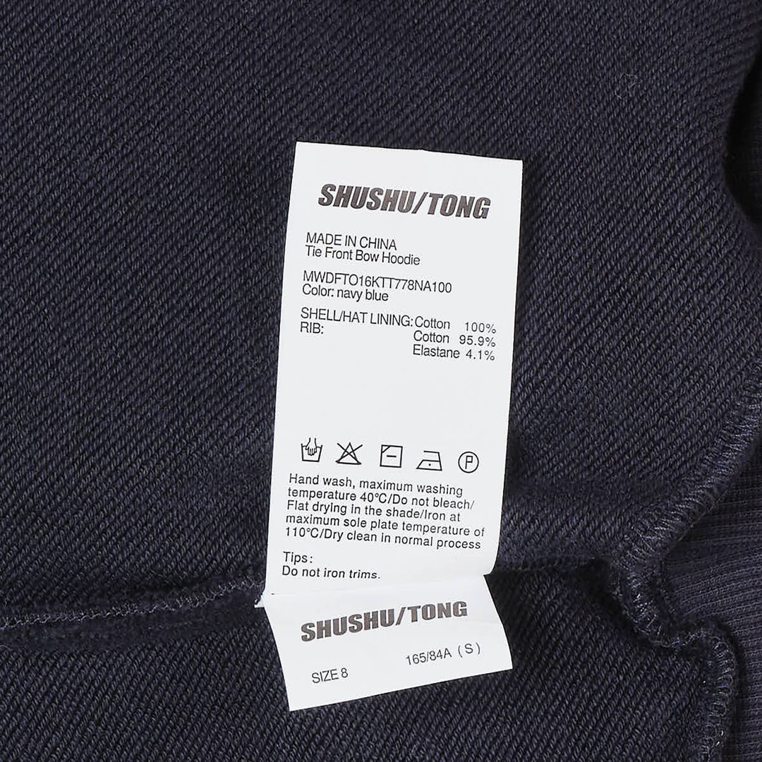SHUSHU/TONG navy Tie Front Bow Hoodie with an oversized self-fabric bow at the waist, open V-neckline, and embroidered logo on the chest