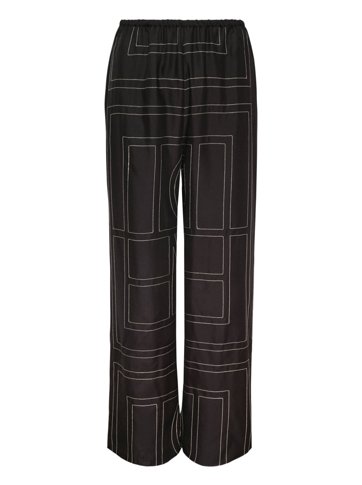 Toteme Monogram Silk Pyjama Pants in black with all-over contrast white stitched geometric panel print and elasticated waistband, wide-leg silhouette, flat lay view