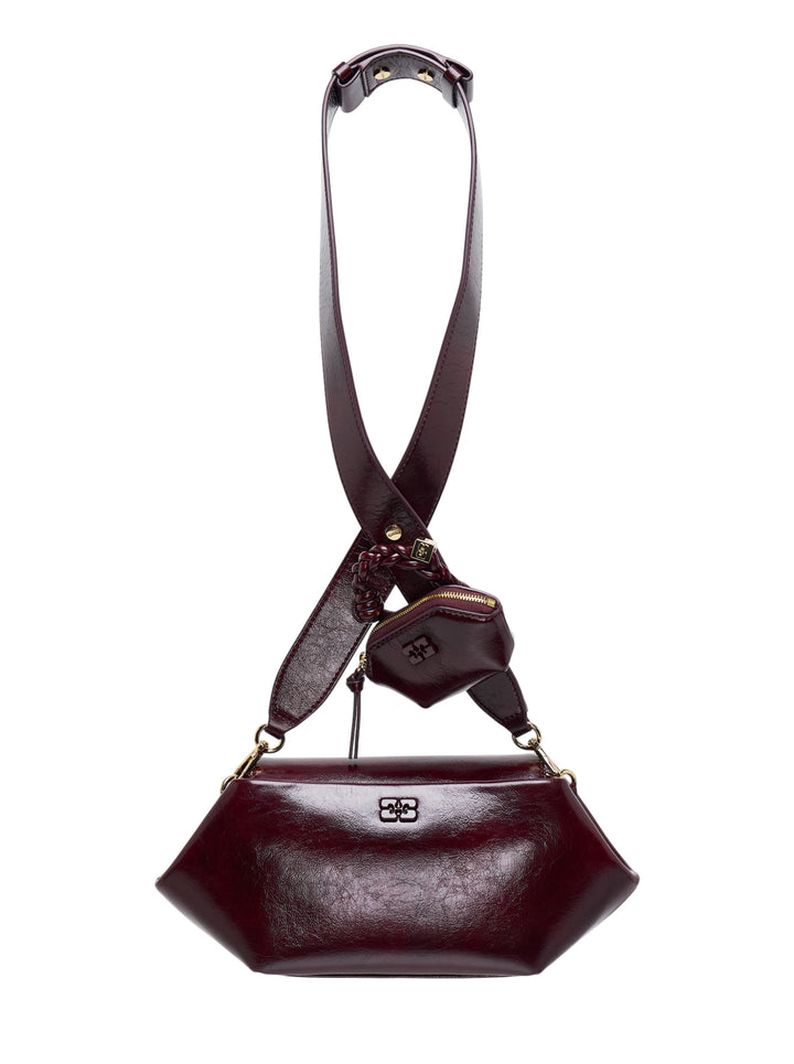 GANNI Bou East/West crossbody bag in glossy deep-burgundy with crossover strap, braided knot detail and attached mini zip pouch
