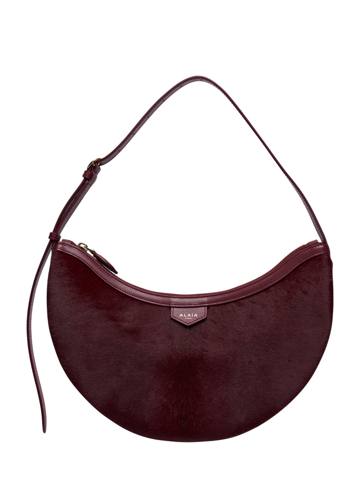 Alaïa Demi Lune haircalf crescent shoulder bag in deep burgundy with smooth leather trim and gold-tone zip closure