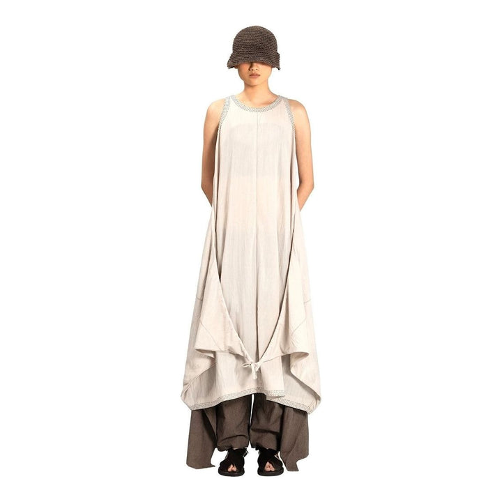 Model wearing an Anaabu black sleeveless midi dress with a voluminous A-line silhouette, asymmetric handkerchief hemline, and fine metallic stud trim at the neckline and hem - packshot