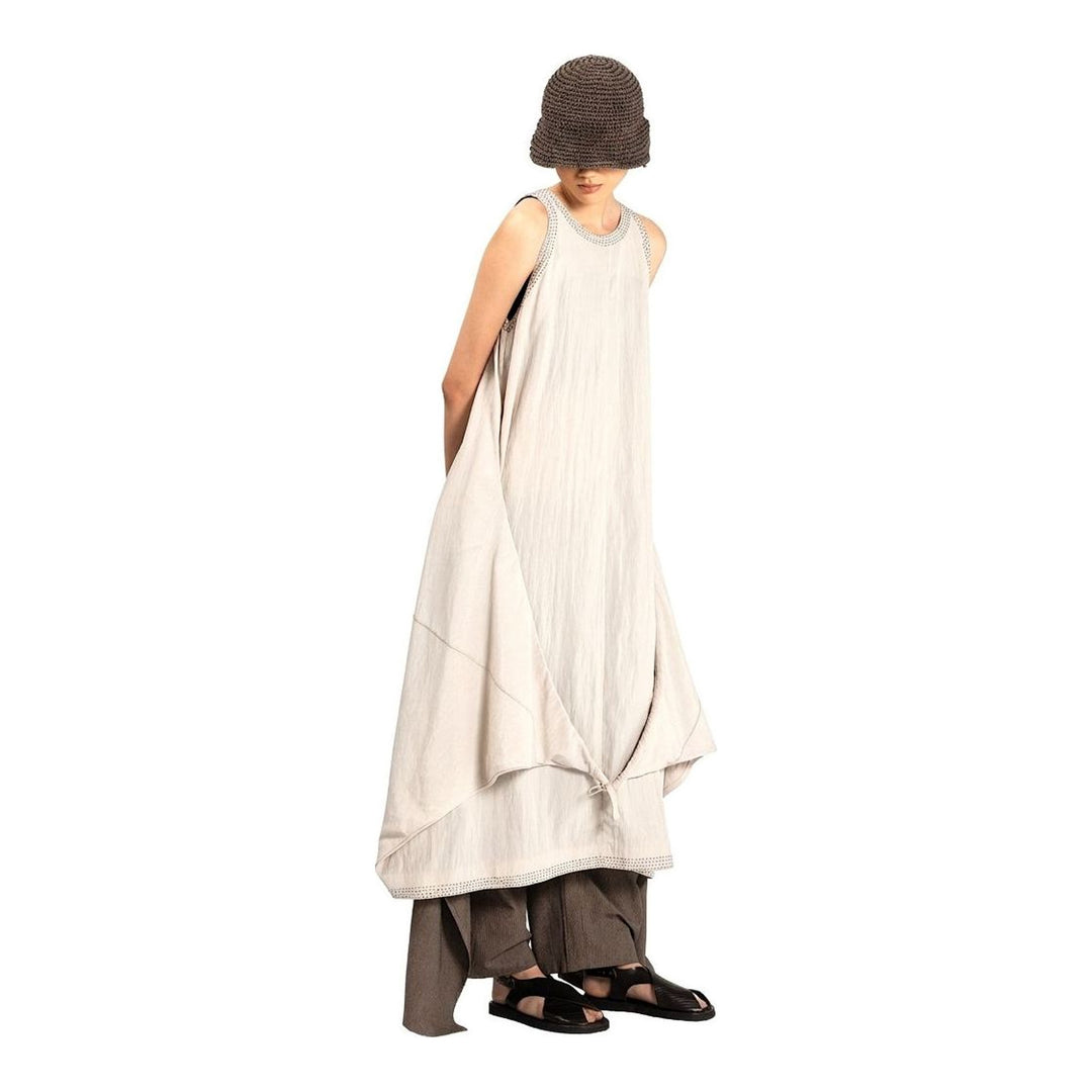 Model wearing an Anaabu black sleeveless midi dress with a voluminous A-line silhouette, asymmetric handkerchief hemline, and fine metallic stud trim at the neckline and hem - packshot