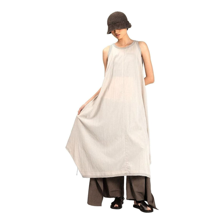 Model wearing an Anaabu black sleeveless midi dress with a voluminous A-line silhouette, asymmetric handkerchief hemline, and fine metallic stud trim at the neckline and hem - packshot