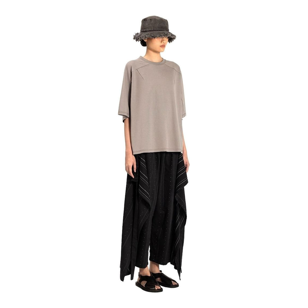 Model wearing the Anaabu Boxy Short Sleeve Tee in black — an oversized, dropped-shoulder silhouette styled over a taupe wide-leg trouser skirt - packshot