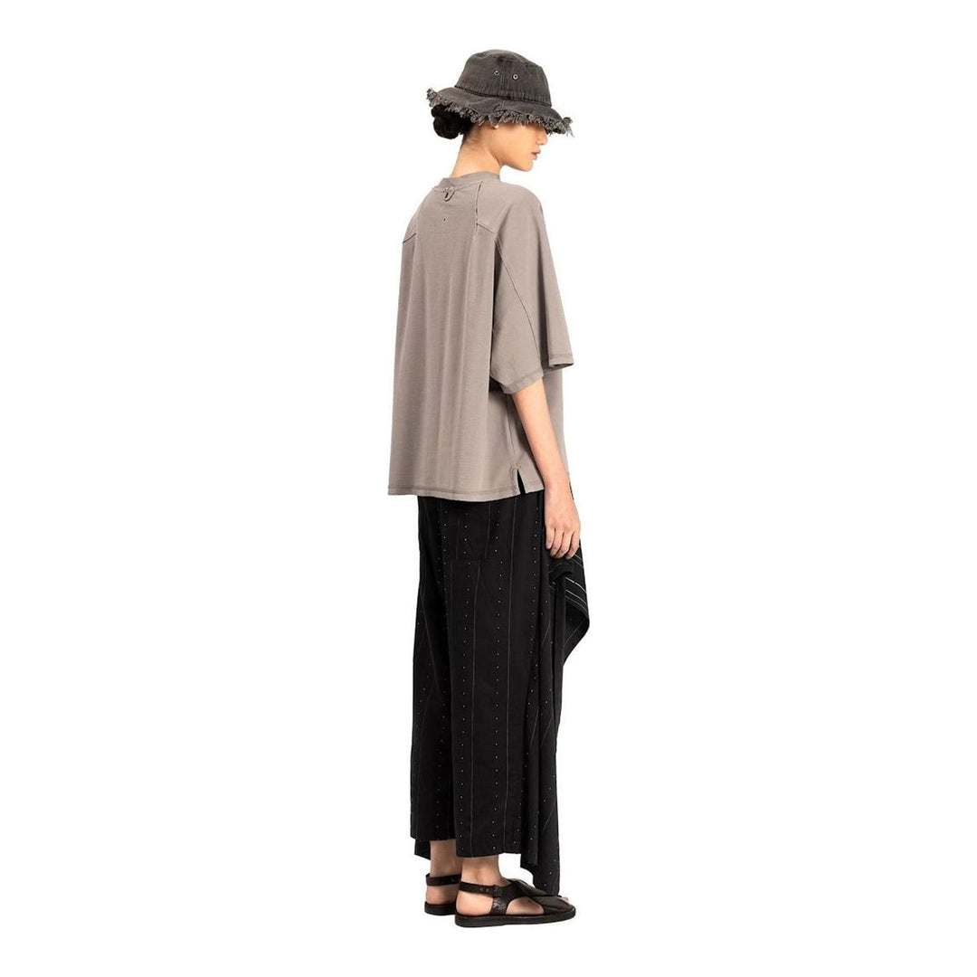 Model wearing the Anaabu Boxy Short Sleeve Tee in black — an oversized, dropped-shoulder silhouette styled over a taupe wide-leg trouser skirt - packshot