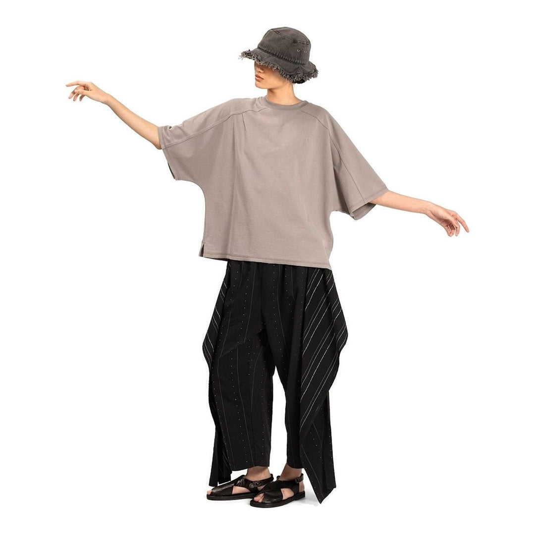 Model wearing the Anaabu Boxy Short Sleeve Tee in black — an oversized, dropped-shoulder silhouette styled over a taupe wide-leg trouser skirt - packshot
