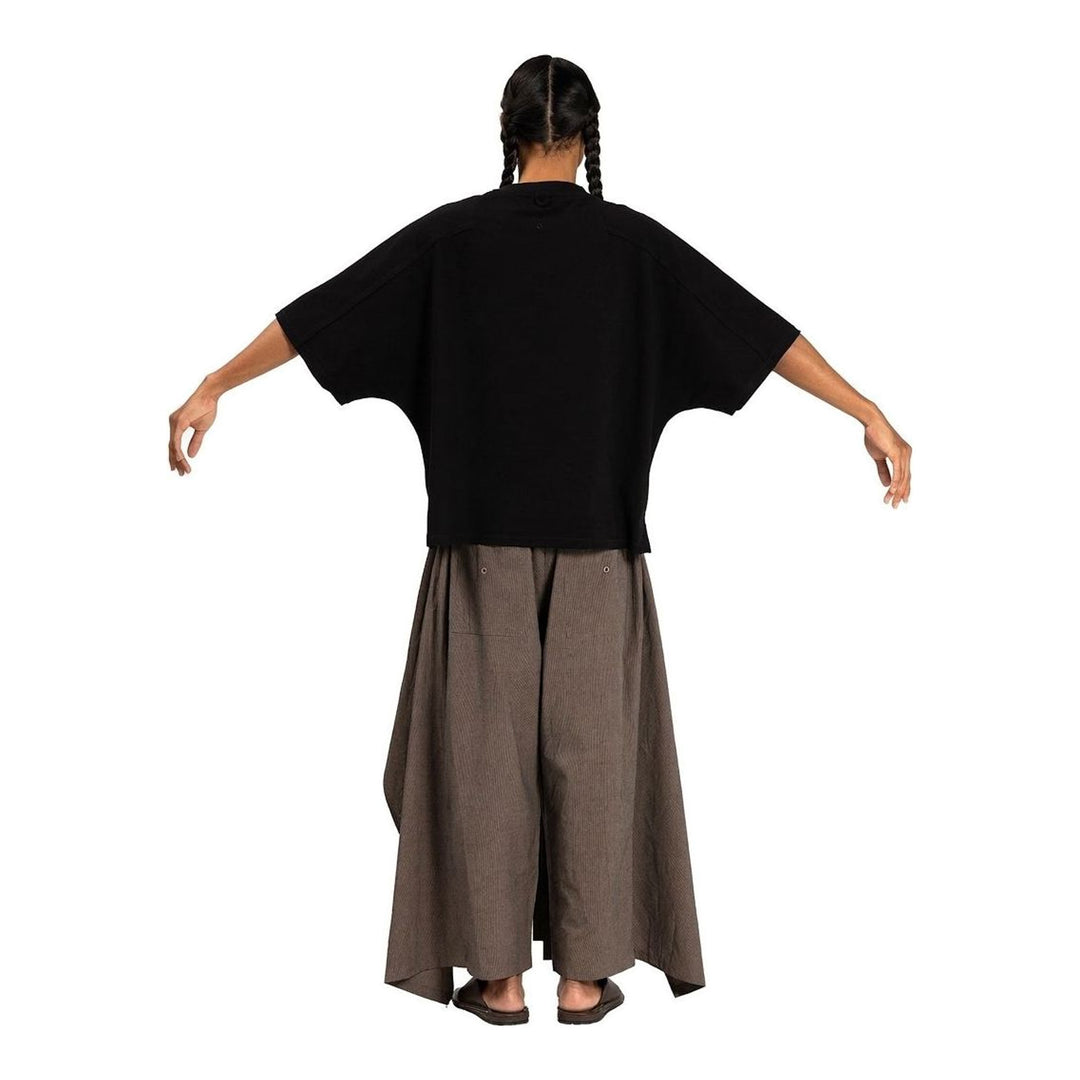 Model wearing the Anaabu Boxy Short Sleeve Tee in black — an oversized, dropped-shoulder silhouette styled over a taupe wide-leg trouser skirt - packshot