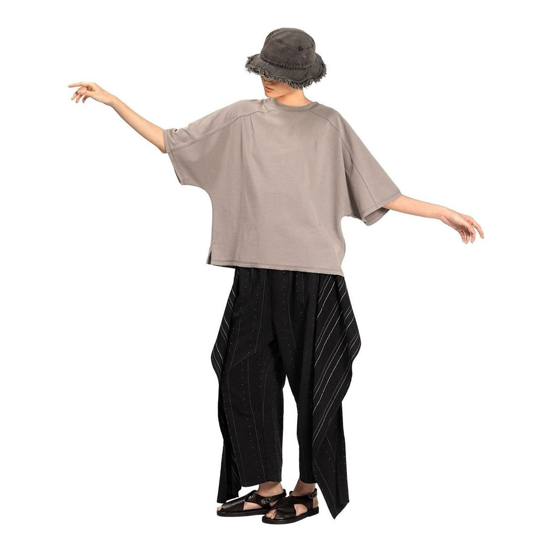 Model wearing the Anaabu Boxy Short Sleeve Tee in black — an oversized, dropped-shoulder silhouette styled over a taupe wide-leg trouser skirt - packshot