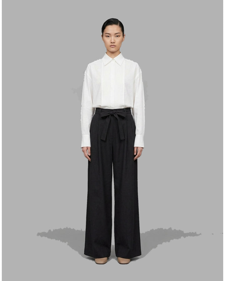 Black high-waisted wide-leg pants with front pleats and a self-tie belt at the waist, shown from the front - front