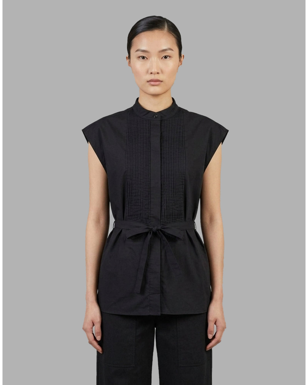 Black sleeveless cotton shirt with pintucked bib front, mandarin collar and self-fabric waist tie - front